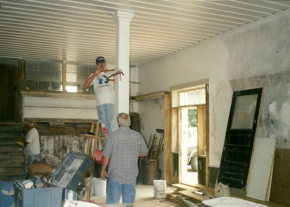 Workers inside the first floor of the building.  The ceiling already has a fresh coat of paint